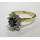 An 18ct sapphire and diamond cluster ring, the deep blue oval cut sapphire surrounded by ten small