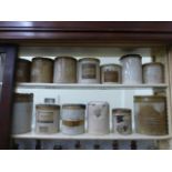 Thirteen stoneware jars, some with paper pharmaceutical labels.