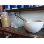 Four glass chemist's bottles and a large pestle and mortar.