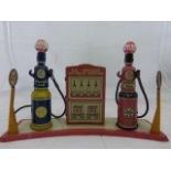 A Marx tinplate forecourt set of two petrol pumps and oil cabinet on a semi circular base.