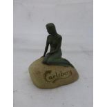 An unusual Carlsberg advertising figure in the form of a nude lady sat on a stylised rock base.