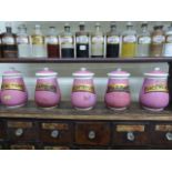 Five pink baluster shaped lidded and labelled medicine canisters.