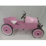 A decorative pink pedal car in excellent condition.