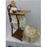 A composite headed doll sitting in a high chair and a lace-covered doll's basket.