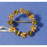 A open circle Wreath Brooch set with six small peridots with seed pearl treffoils between, mounted