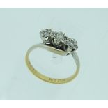 A three stone diamond Ring, set on the cross, mounted in platinum with an 18ct yellow gold shank,