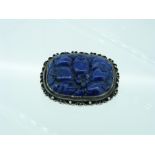 A Chinese Brooch, set with an oval carved lapis lazuli, of fruit and flowers, in a silver mount, the