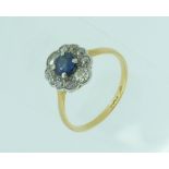 A sapphire and diamond cluster Ring, the circular cut sapphire surrounded by ten millegrain set