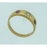 A 9ct yellow gold Ring, gypsy set with two pale rubies and one small diamond in the centre, Size O.