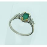A modern emerald and diamond Ring, the oblong step cut emerald with six small diamonds on each