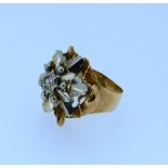 A large flowerhead Ring, in yellow and white metal, the centre mounted with a small diamond point,