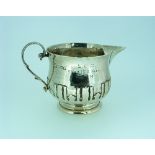 A George V hammered silver Cream Jug, by Pearce & Sons, hallmarked London, 1913, with scroll