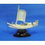 An early 20thC oriental carved ivory Junk, "Syriam Ferry", with main sail, figures and canopy, on