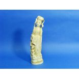 A Japanese carved ivory figure of a Maiden, Meiren, standing wearing long robes beside rockwork