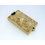 A late 19thC Chinese ivory Dance Card, the covers carved with figures and trees in fenced gardens