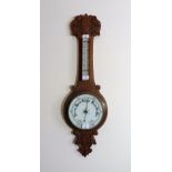 An Edwardian carved oak Aneroid Barometer and thermometer, 33½in (85cm) high. Provenance: Stoodley