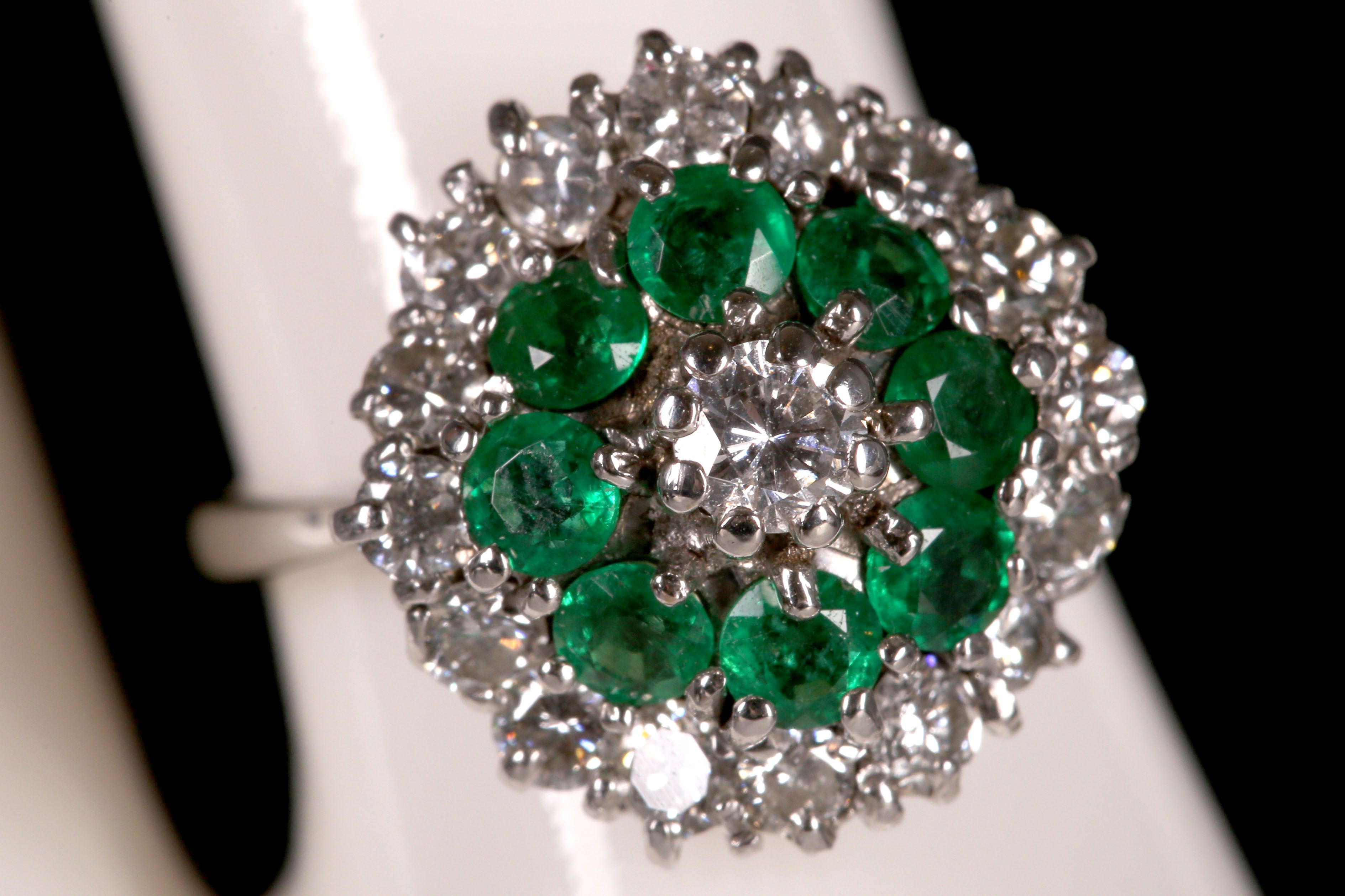 An 18ct white gold, emerald and diamond cluster ring.