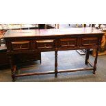 An oak dresser base, having two double fronted drawers, supported on three turned front legs with