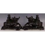 A pair of 19th Century Chinese dark wood carvings of a child riding a buffalo, each supported by