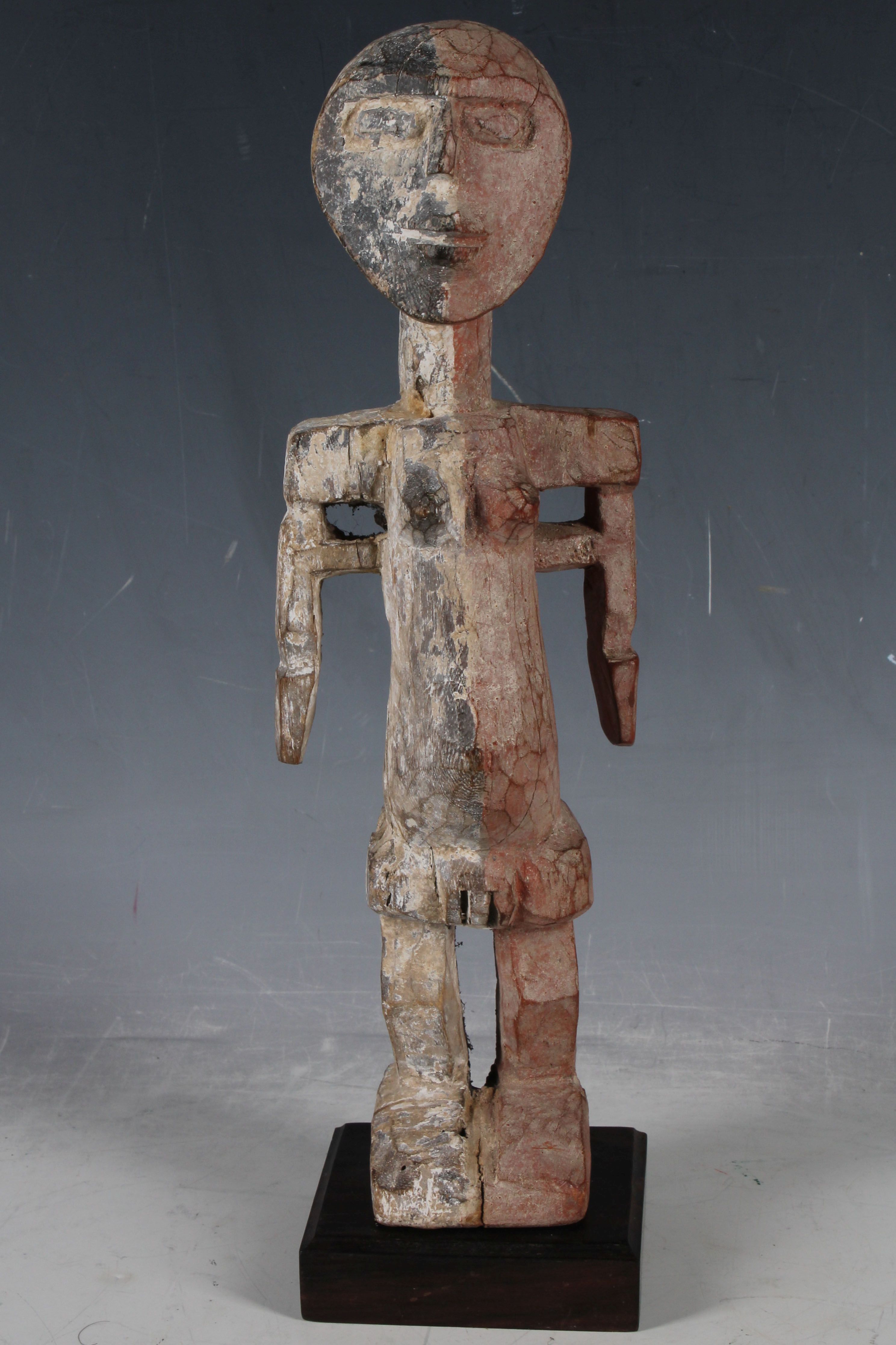 A carved African tribal figure, female fertility with black and red organic kaolin pigment, possibly