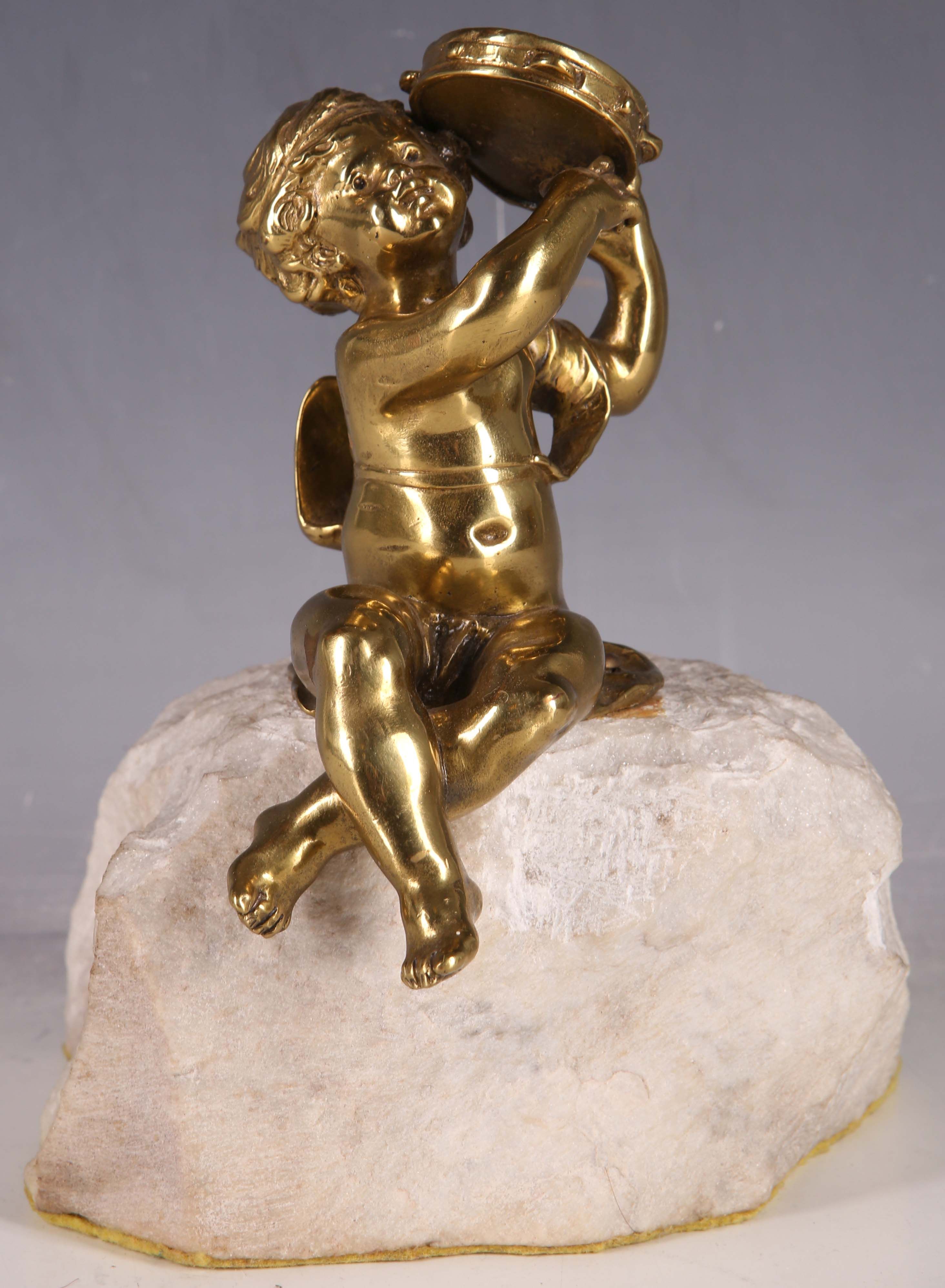 A late 19th Century solid brass statue of a child with tambourine, raised on a rough hewn quartz