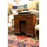 A Georgian style mahogany kneehole desk, with frieze drawer over an open recess with cupboard door