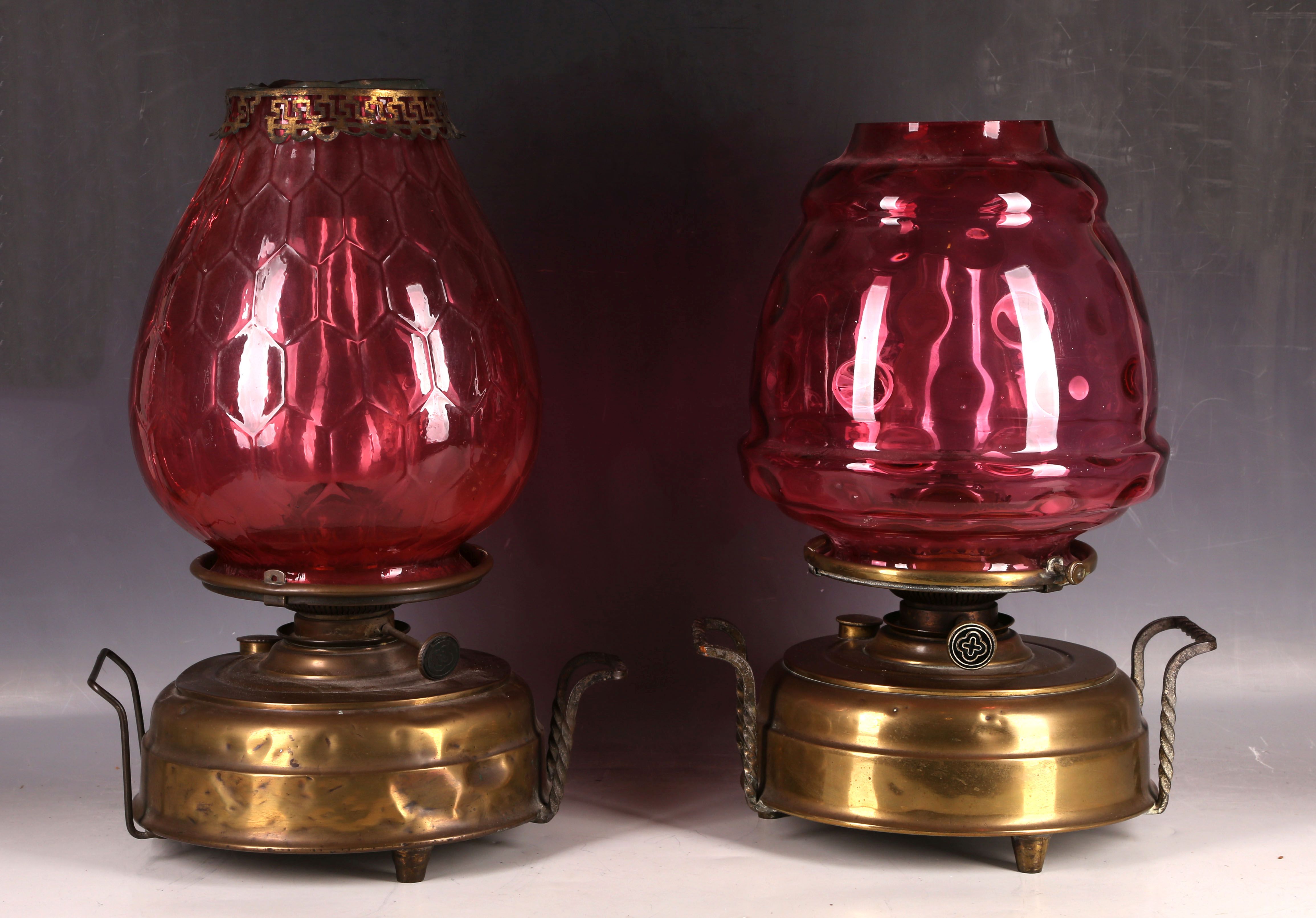 A pair of Edwardian brass oil lamps, having large dimpled cranberry glass shades (one AF).