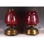 A pair of Edwardian brass oil lamps, having large dimpled cranberry glass shades (one AF).