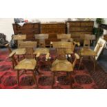 A set of six oak elbow chairs with bar back and pierced back rest over a solid seat flanked by arm