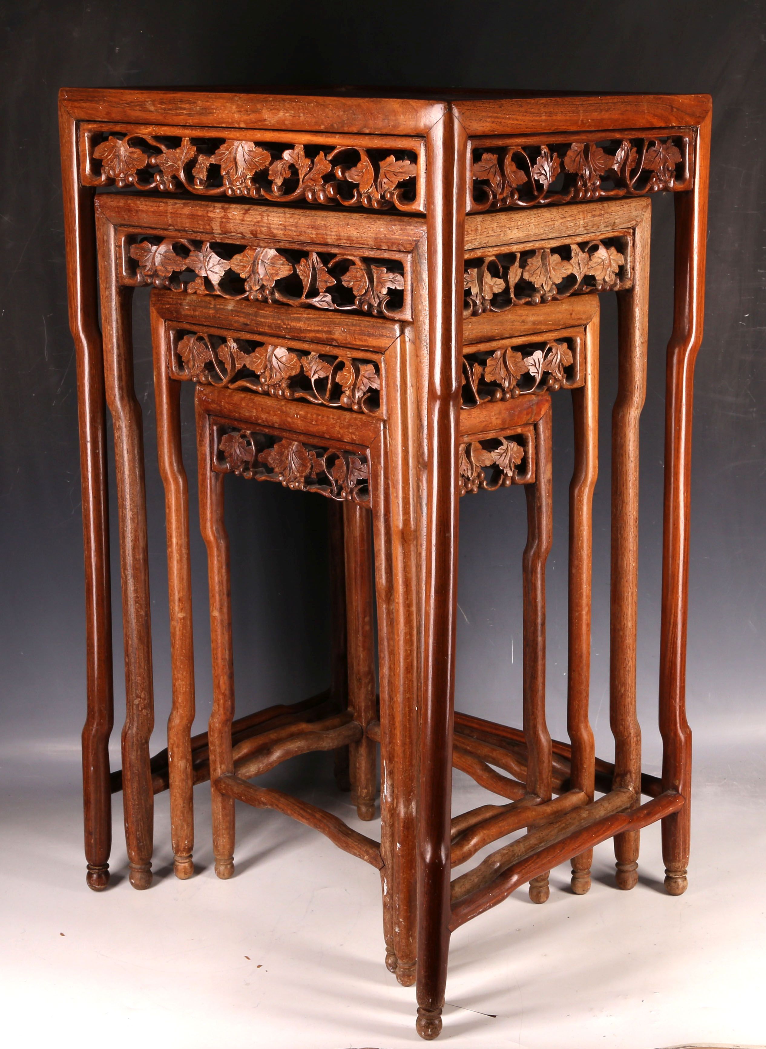 A nest of four Chinese hardwood tables, having carved aprons and inset tops. (4)