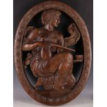 An 18th Century oval double sided oak carving of a kneeling apothecary set within an oval egg and