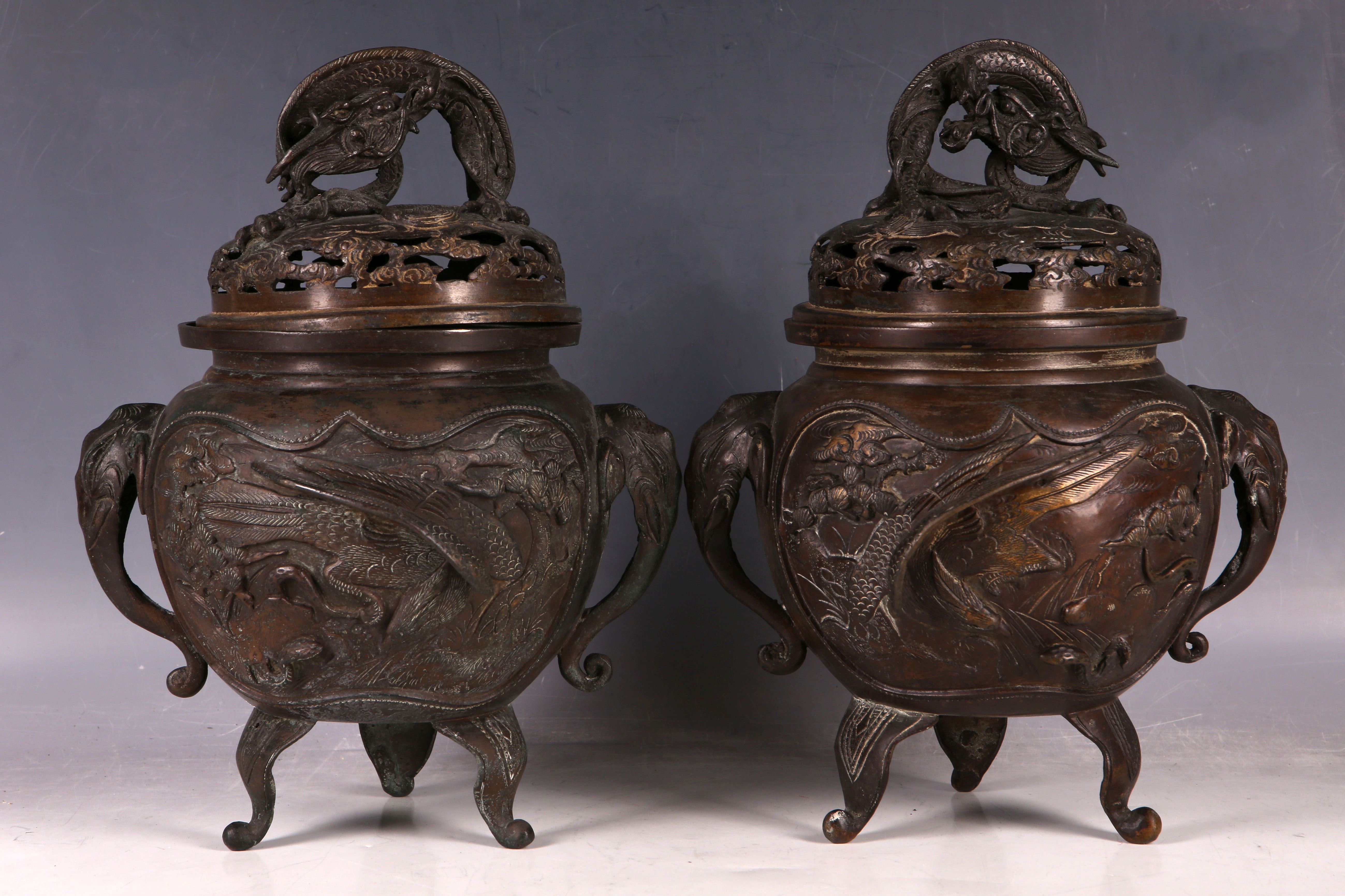 A pair of Japanese bronze incense burners, the body of each decorated with two panels with a pair of