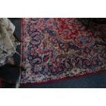 An antique 'Indo / Persian' rug, with central arabesque cartouche on a cherry field with vase and