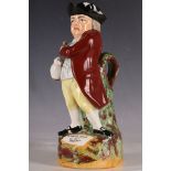 A Staffordshire earthenware Toby jug, modelled as 18th Century man holding pipe and jug of ale,