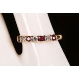 An 18ct yellow gold, ruby and diamond set half eternity ring.