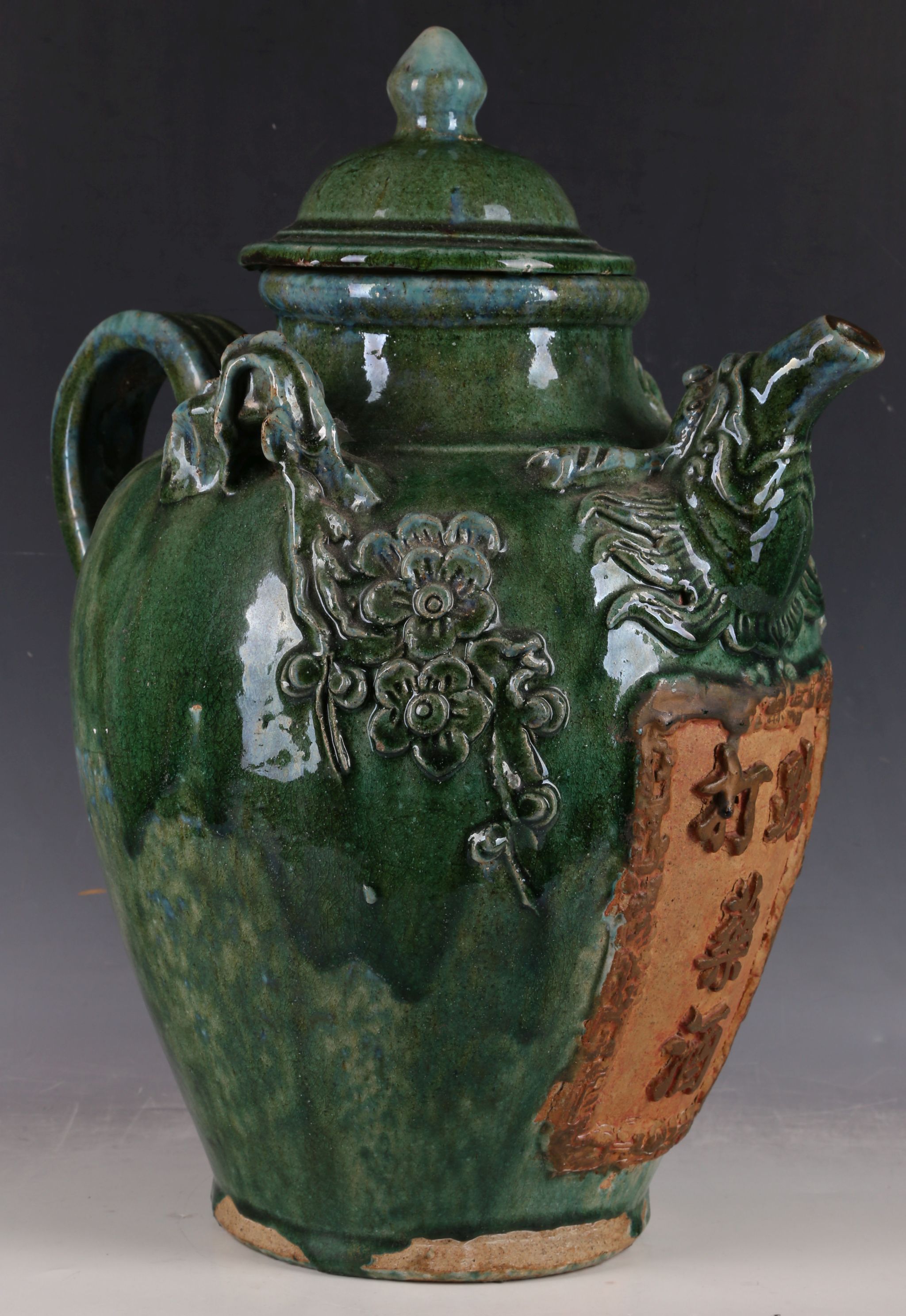 A large Chinese green glazed wine jug and cover, with peony modelled decoration, a mythical beast