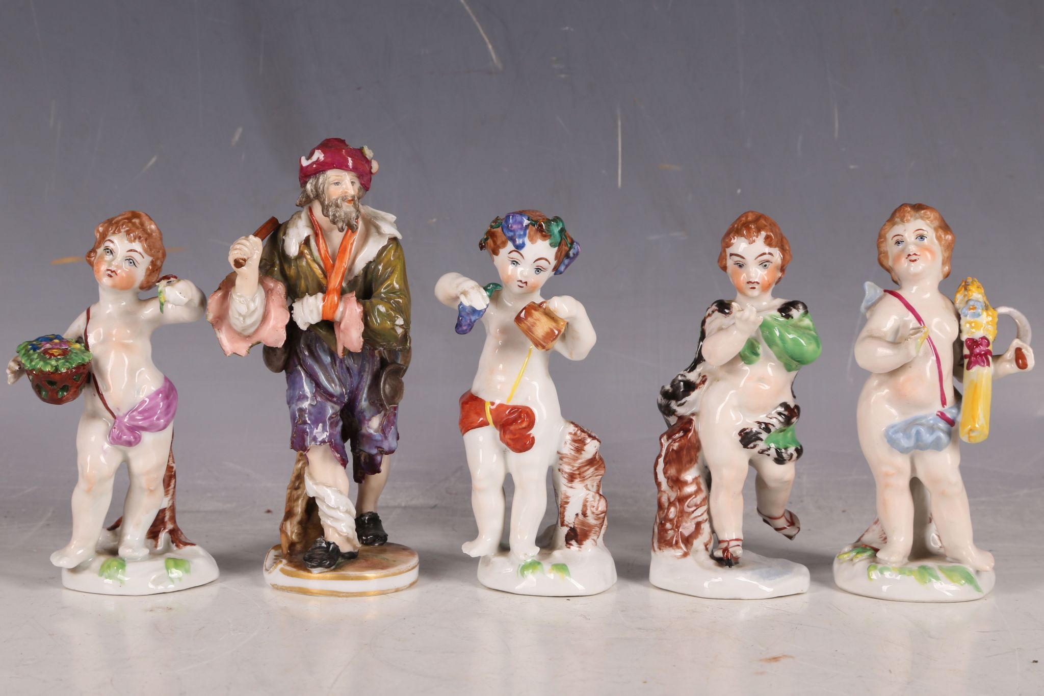 Five 19th Century Crown Naples porcelain figures, to include putti, two carrying flowers, and a