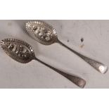 A pair of hallmarked silver berry spoons, both decorated with roses with scrolling decoration to