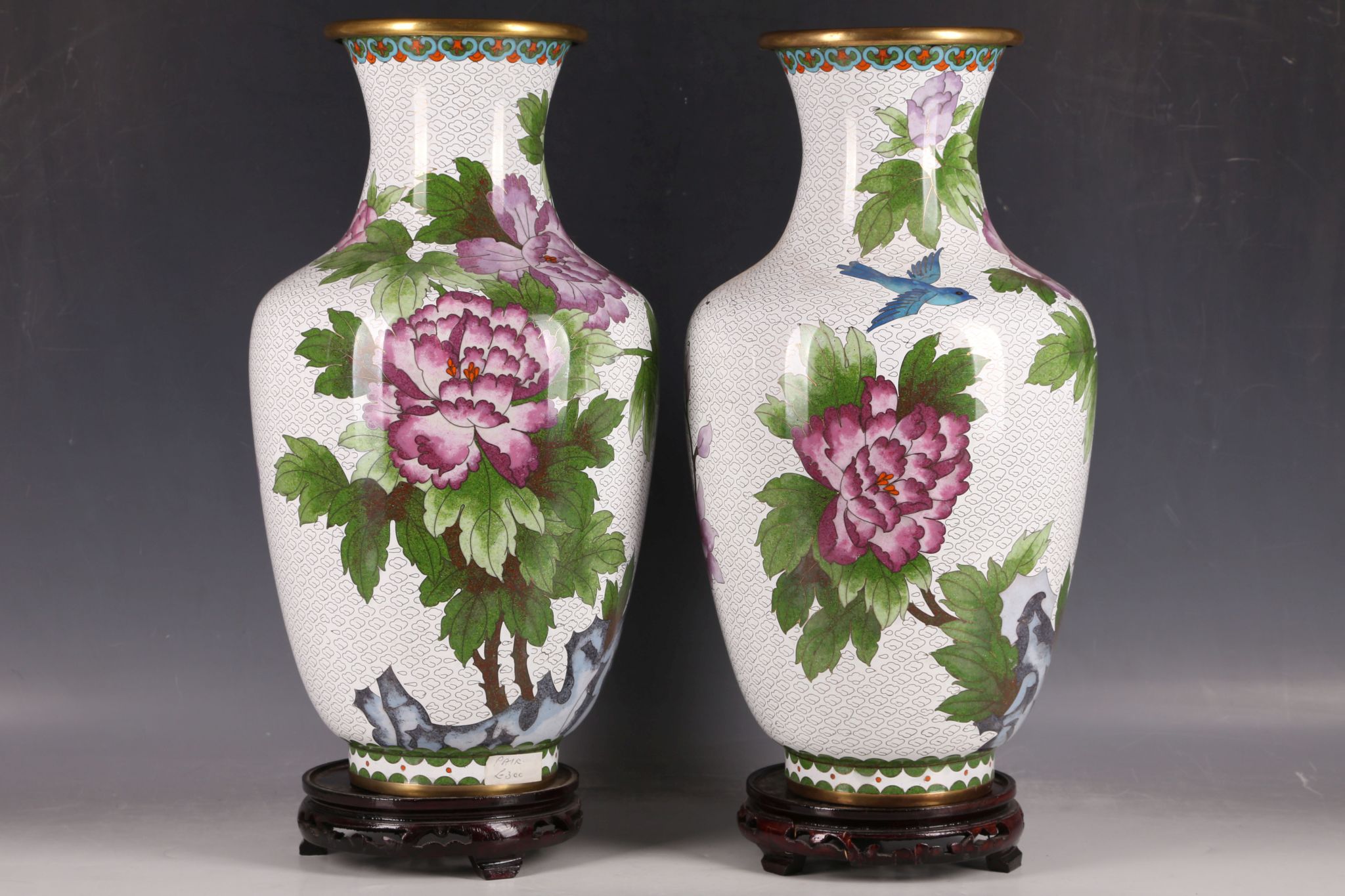 A pair of large cloisonné vases, with birds among flower blossoms on white ground, on wooden stand.