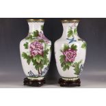 A pair of large cloisonné vases, with birds among flower blossoms on white ground, on wooden stand.