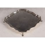 A hallmarked silver square section card tray, decorative edge, with canted corners, raised on four