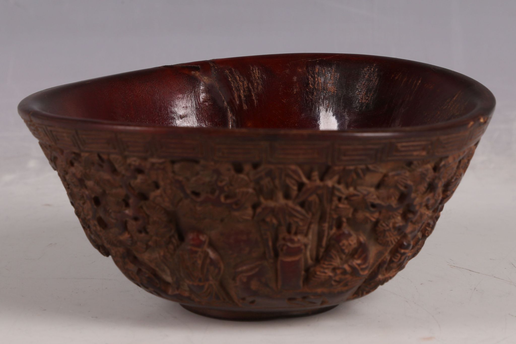 A Chinese ox horn bowl, carving to flank of the eight immortals in garden / forest scene, 12.5cm