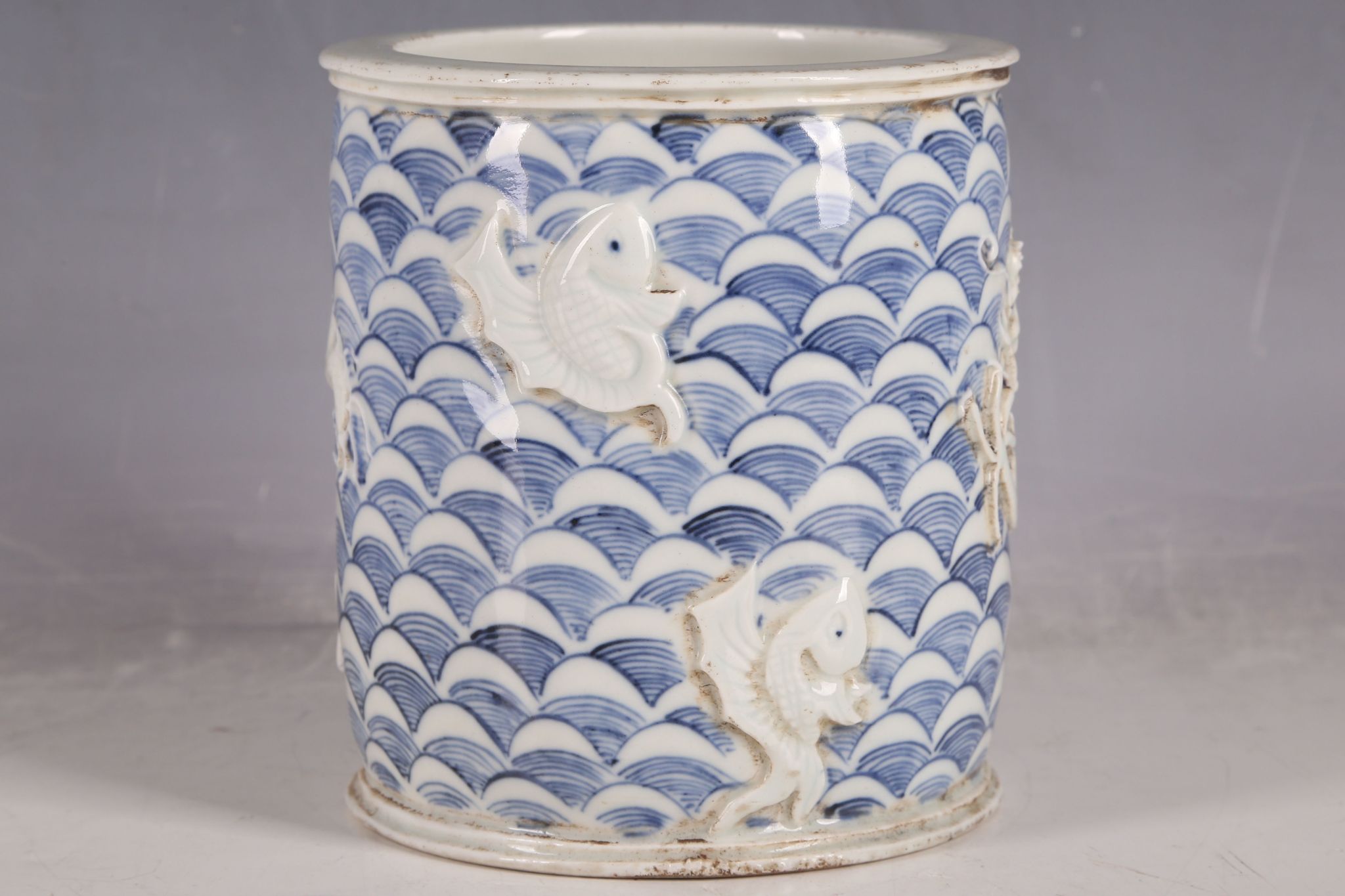 A Chinese brush pot, blue wave decoration with applied five toe, open mouth dragon, chasing