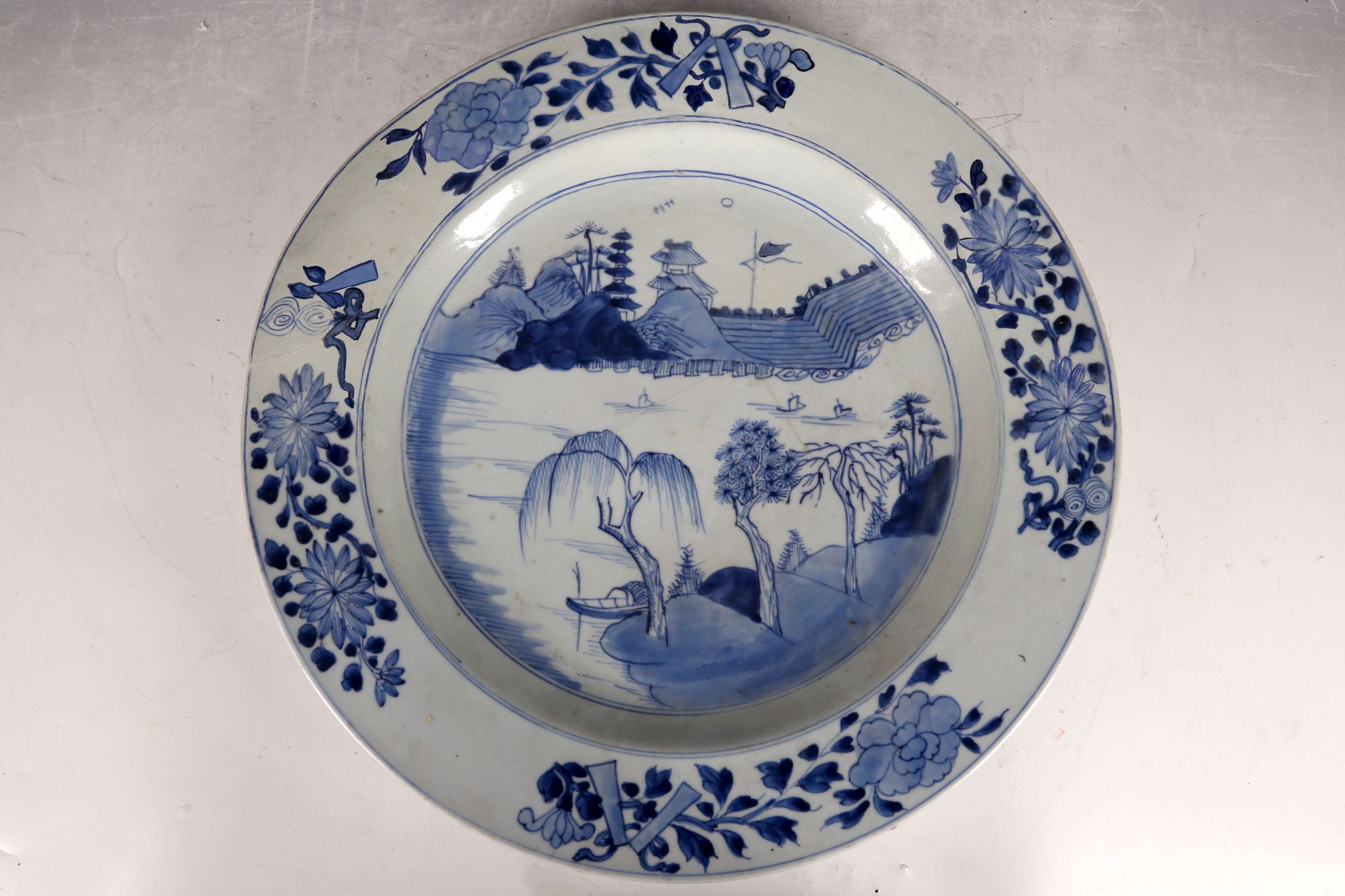 A large Chinese 19th Century provincial blue and white dish, decorated with boats and pagodas,
