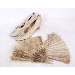 A pair of 1920s white leather ladies shoes, with two lace fans. Shoes have ankle strap and bow