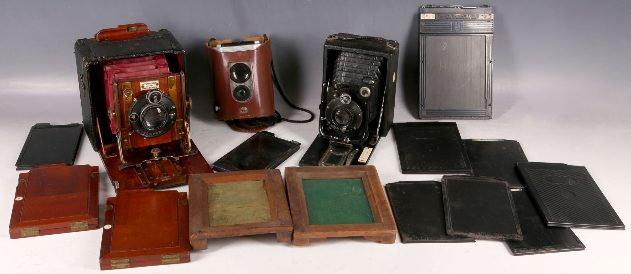 A vintage Sanderson camera, mahogany box red bellows with a set of three plates, a portable