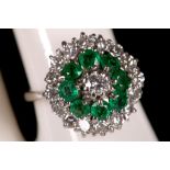 An 18ct white gold, emerald and diamond cluster ring.