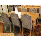 A Continental bleached walnut dining table, with six floral upholstered dining chairs and matching