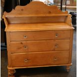 A pine dressing chest of drawers, with three quarter gallery over three long drawers, raised on