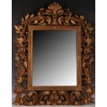 A very early 20th Century Rococo style carved wood wall mirror, having leaf and scrolling decoration
